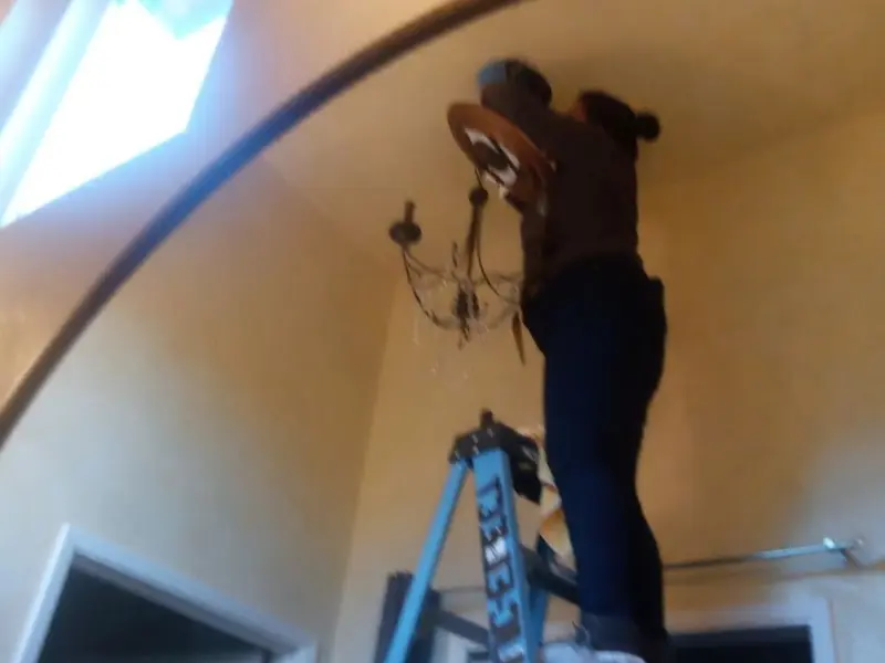 Electrician installing a chandelier in a Saco residence